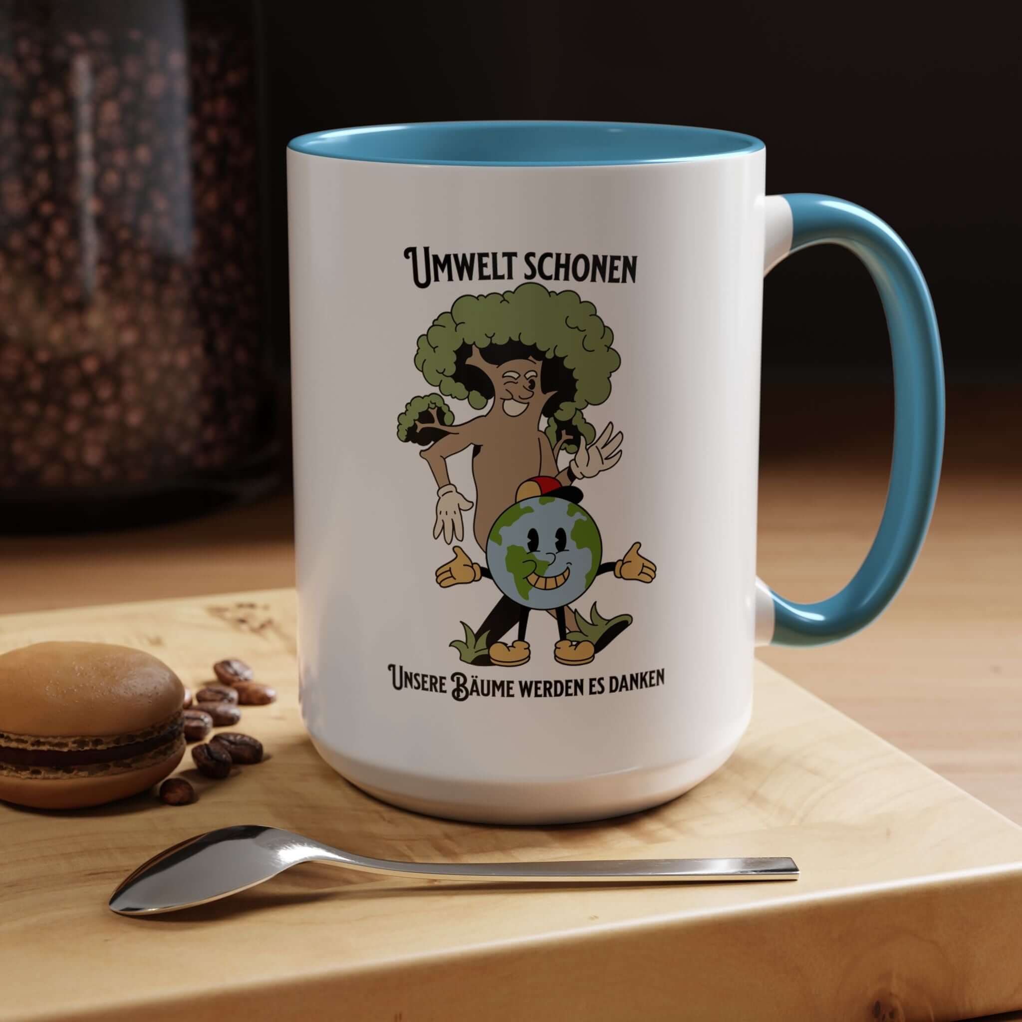 Kaffeetasse Umweltliebhaber Geschenk mit lächelnder Erde und Baum, schwarzer Innenseite und Henkel, auf Holztisch mit Löffel und Macaron.