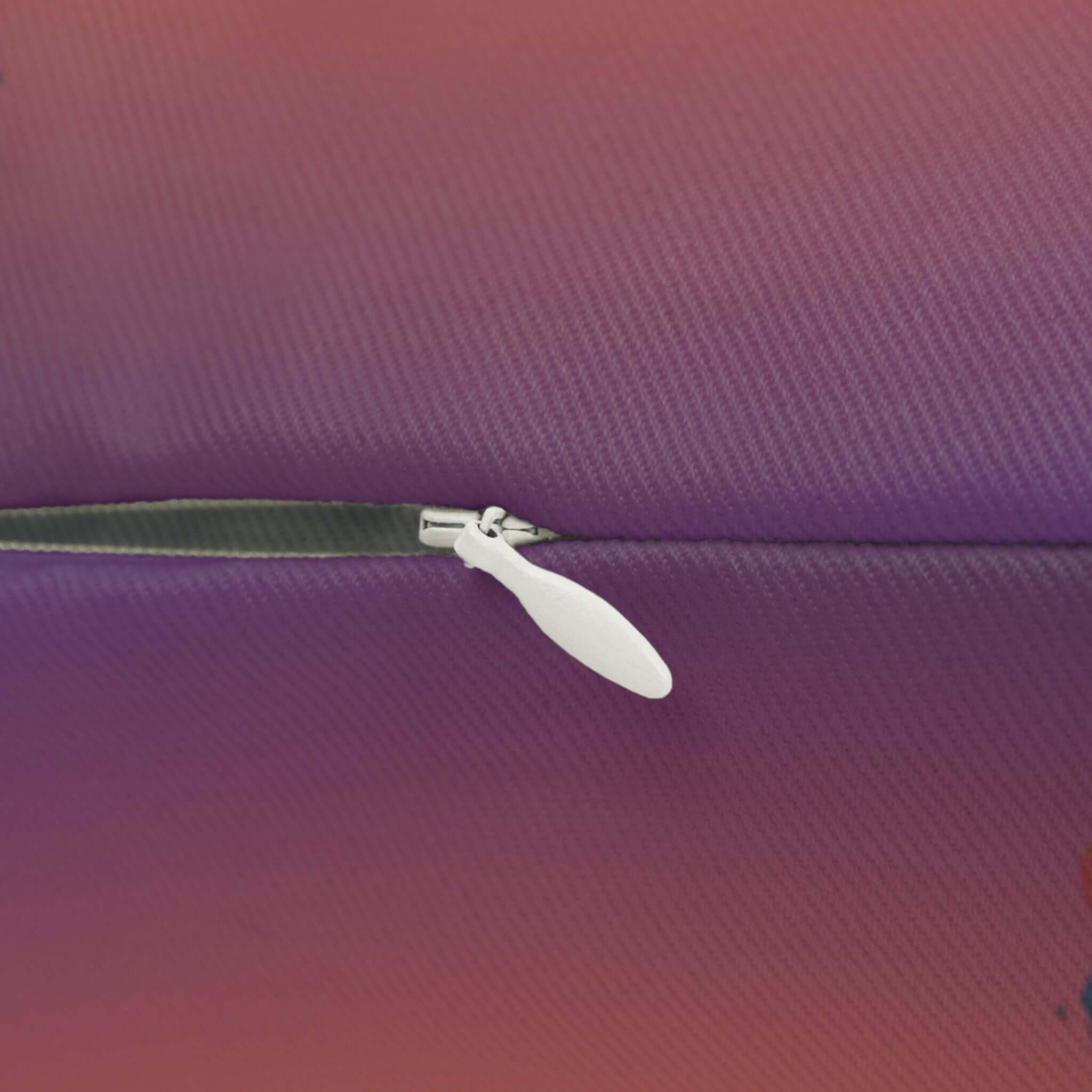 Nahaufnahme des Reißverschlusses eines Lendenkissen mit Phönix Motiv zum Kuscheln, lila bis rote Farbverläufe sichtbar.