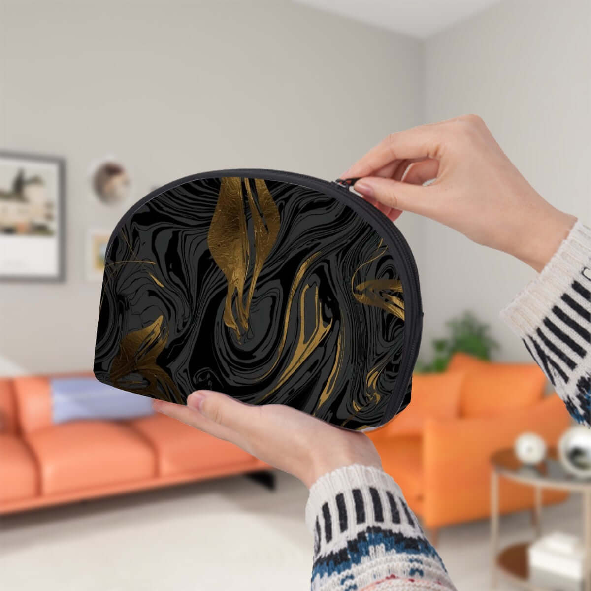 Person holding a stylish Aufbewahrungsbeutel-Set (2 Stück) with black and gold swirl design in living room background.