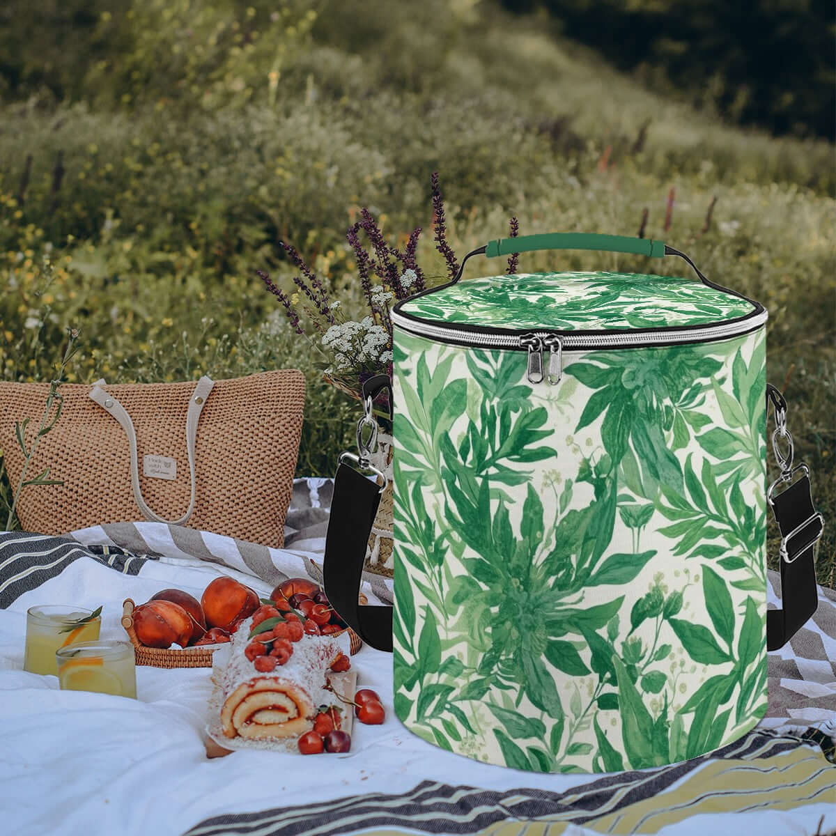 Grüne Camping-Kühltasche, tragbar, isoliert und wasserdicht, mit Picknick im Freien, auf Decke mit Früchten und Getränken.