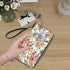 Clutch-Geldbörse für Damen - Stilvoll & Praktisch mit Blumendruck, handgehalten auf Holztisch mit Blumen und Geschenk im Hintergrund.