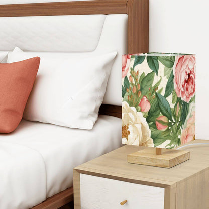 Quadratische Tischlampe mit Blumenmuster auf Holztisch neben einem Bett, Leinen und Gummiholz Material, warm und gemütliche Beleuchtung.