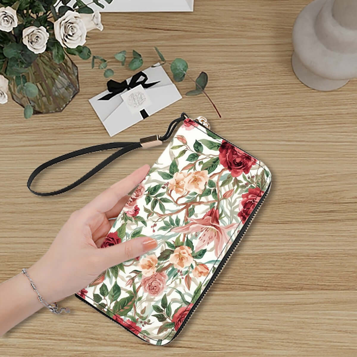 Hand holding floral Clutch-Geldbörse für Damen with PU material and UV print design on a wooden table.