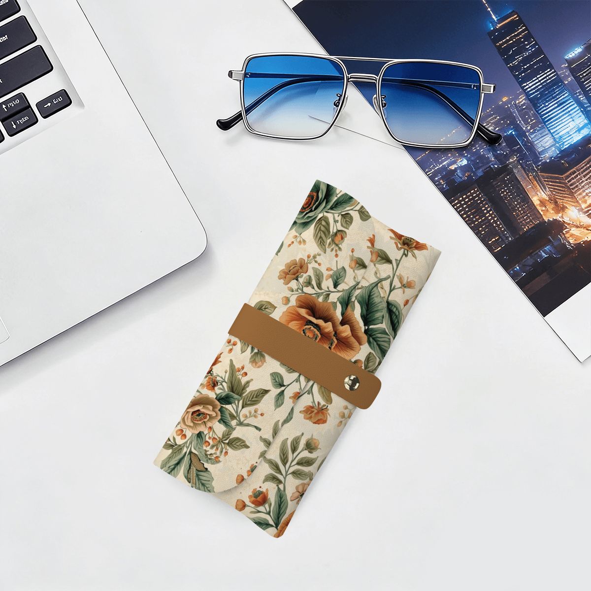 Brillenetui aus PU-Leder mit Blumenmuster neben Sonnenbrille und Laptop, ideal für die Aufbewahrung von Brillen, stilvoll und funktional.